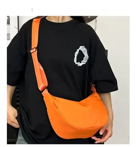 Bright orange nylon crescent crossbody bag with adjustable wide strap on a model