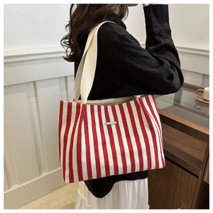 Detail view of large capacity red and white striped canvas tote bag with metal label
