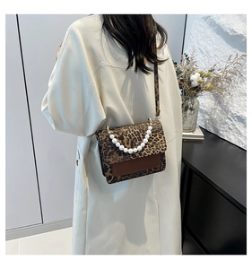 Detail of leopard print crossbody bag featuring large pearl handle and textured flap