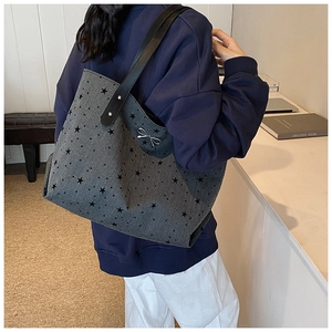 Detail of grey canvas tote bag featuring black star prints and a small silver metal bow