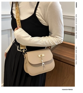 Detail of beige crossbody bag with golden deer pendant and woven jacquard strap