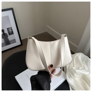 Détail d'un sac sous le bras minimaliste crème avec surpiqûres verticales tenu à la main