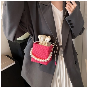 Detail of rose pink mini bag with large pearl handle and gold chain strap on model