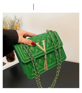 Detail view of emerald green quilted crossbody bag with golden V-logo and chain strap