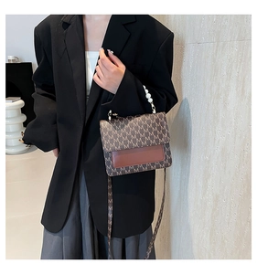 Detail of vintage crossbody bag with letter print pattern and elegant pearl handle strap