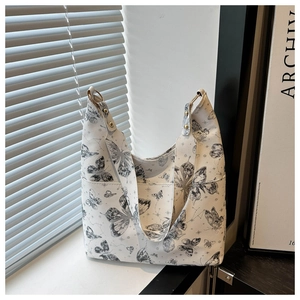 Détail du sac cabas blanc avec imprimés papillons noirs et accents métalliques dorés