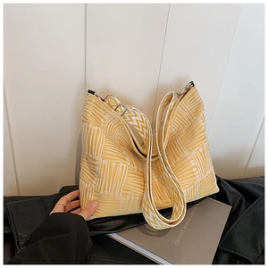 Close-up of yellow jacquard knit canvas bag with geometric patterns and wavy shoulder strap
