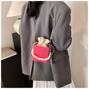 Sac seau tissé magenta avec grande poignée en perles et chaîne dorée porté par mannequin