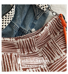 Detail of woven geometric pattern bag with checkerboard strap and metal chain