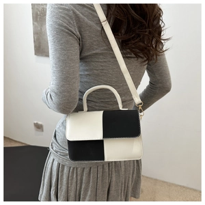 Borsa a tracolla bicolore bianco e nero minimalista indossata su un abito grigio