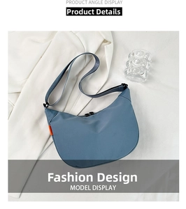 Detail of blue crescent crossbody bag with zipper and orange tag on white blazer