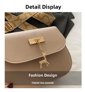 Detail of light beige faux leather bag with golden deer pendant and fine stitching
