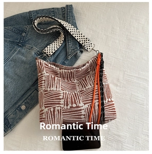 Detail view of striped canvas tote with checkerboard strap and phone for size reference