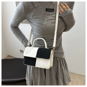 Dettaglio di una borsa chic in pelle bicolore bianco e nero indossata da una modella