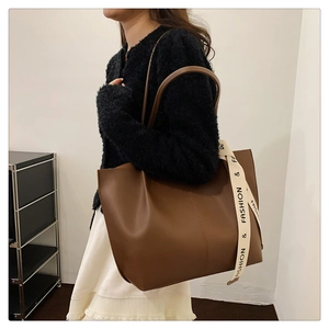 Detail view of large brown faux leather tote with cream FASHION ribbon accent