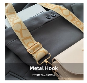 Detail of wide woven strap with golden metal hardware hooks on beige square crossbody bag