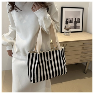 Detail of striped canvas tote bag with metal nameplate in a cozy home setting