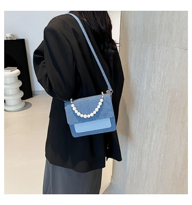 Detailed back view of a blue denim crossbody bag featuring an elegant pearl handle strap