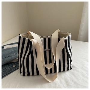 Detail of black and white striped canvas tote bag with metal logo and wide straps