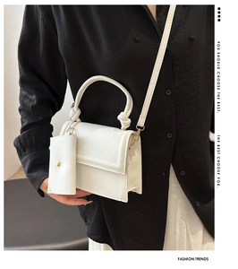 Detailed view of white minimalist square bag with matching mini pouch on a model