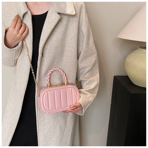 Close-up of pink vertical striped handbag with gold chain strap and twisted top handle