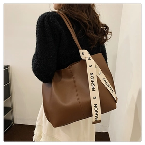 Detail of a large brown leather tote bag with fashion printed webbing and stitching