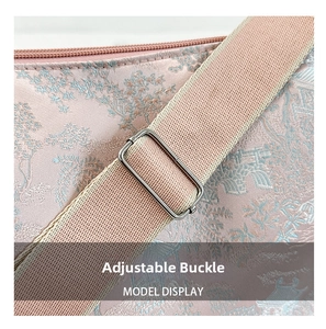 Detail of embroidered pink brocade bag with adjustable metal buckle and wide strap
