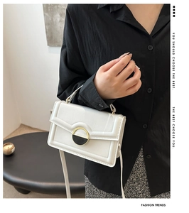 Minimalist white crossbody bag with elegant round metal buckle and slender strap detail