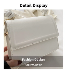 Close-up of white leather handbag featuring a knotted handle and gold metal ring detail
