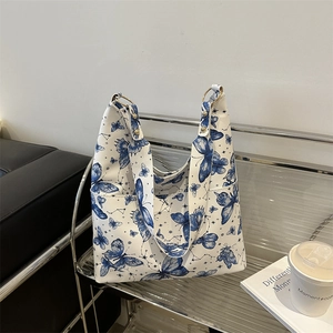 Sac fourre-tout blanc avec imprimé papillon bleu et étoile, anneaux dorés sur étagère