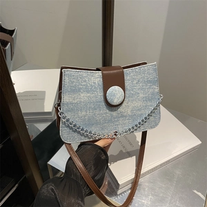 Blue denim tote bag with rhinestones, brown leather flap, and silver chain detail