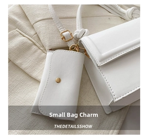 Detail of white PU leather crossbody bag with golden clasp and matching coin purse charm