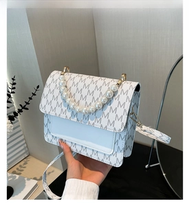 Close-up of white PU shoulder bag featuring M-letter pattern and pearl beaded handle