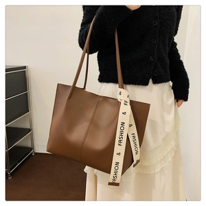Brown faux leather tote bag detail with fashion ribbon strap and vertical stitching
