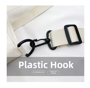 Dettaglio del gancio in plastica nera e tracolla intrecciata su una borsa in nylon bianco