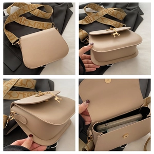 Detail view of beige saddle bag with gold deer pendant and printed wide shoulder strap