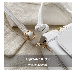 Detail of adjustable strap buckle and gold hardware on a minimalist white crossbody bag