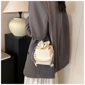 Détail du mini sac seau blanc texturé avec anse en perles et chaîne dorée