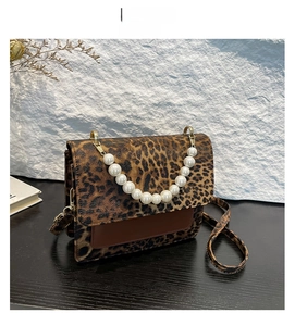 Close-up of leopard print crossbody bag with pearl handle and golden hardware lock