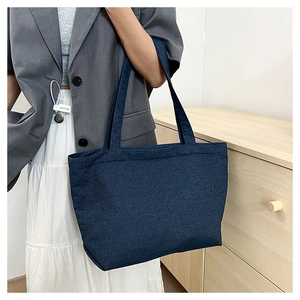 Detail shot of a dark blue denim tote bag made of high-quality fabric on a shoulder