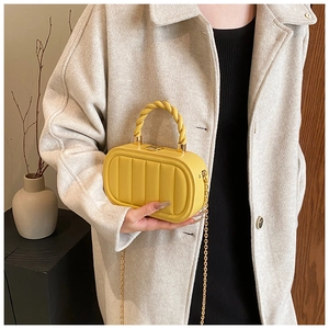 Close-up of yellow textured PU leather box bag with woven handle and gold chain strap