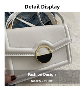 Detail of white lychee leather texture and circular gold hardware on a minimalist bag