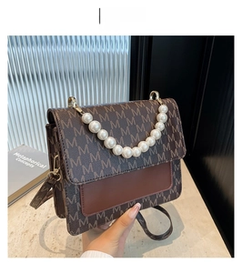 Close-up of monogram pattern leather bag with large pearl handle and metal hardware