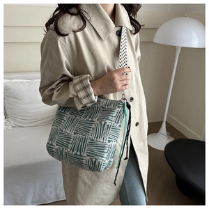 Close-up of green and cream knitted tote bag featuring a black and white checkered strap