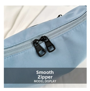 Detail of smooth double metal zippers on light blue nylon crossbody bag with fabric texture