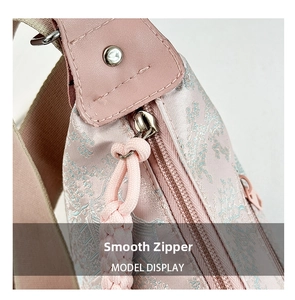 Close-up of smooth silver zipper and floral jacquard fabric on pink crossbody bag