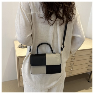 Vista a tracolla di una piccola borsa quadrata bicolore con design patchwork nero e beige