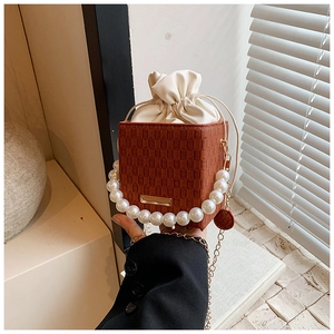 Dettaglio della borsa a secchiello marrone vintage con manico di perle e coulisse