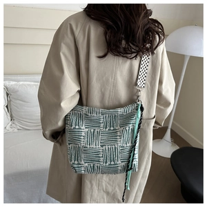 Detail of green geometric woven canvas tote bag with textured shoulder strap worn by model