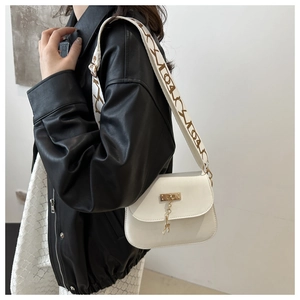 Détail du sac bandoulière blanc avec large sangle à motifs et breloque dorée cerf